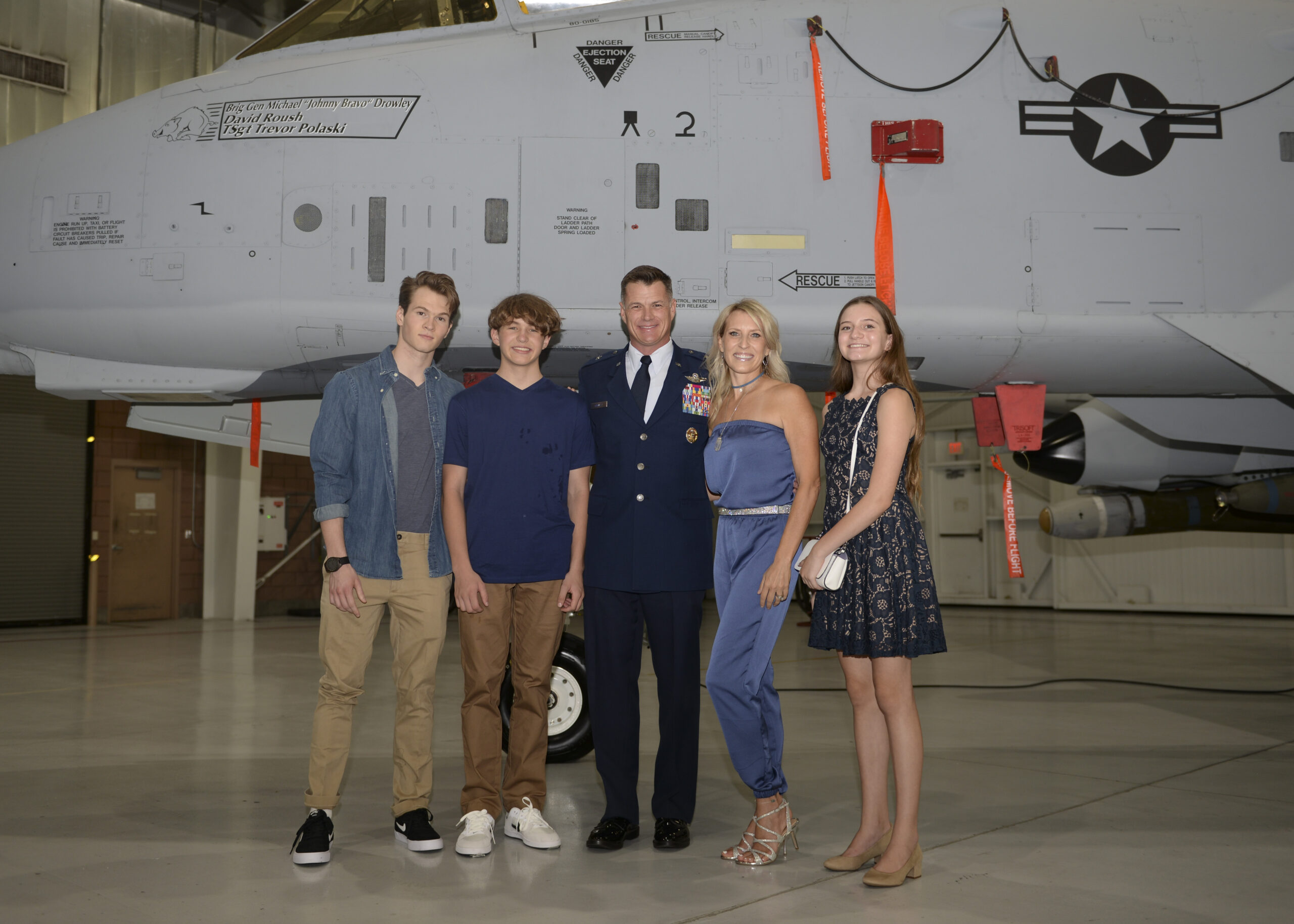 Dr. Drowley and her family posing for a photo with an airplane in the back.