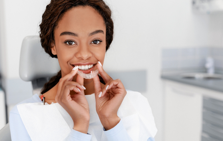Dental Treatment Concept. Close up of young black woman holding invisible aligner, whitening tray, free space