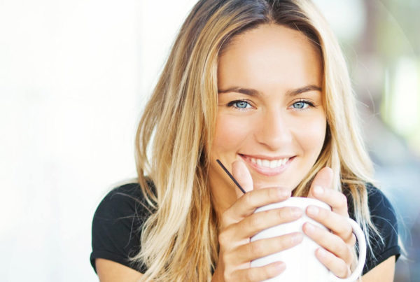 woman smiles over coffee wondering on veneers or braces