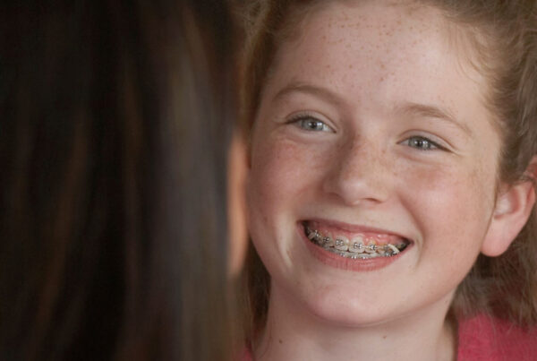 girl smiles showing off her braces for kids