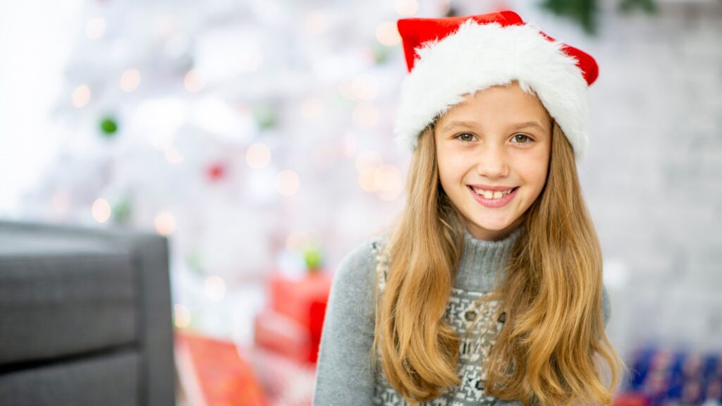 girl with santa hat smiles as she hears stocking stuffer ideas