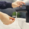 Woman's hands cleaning clear retainer in sink, running under faucet, Saxe Orthodontics clean retainers